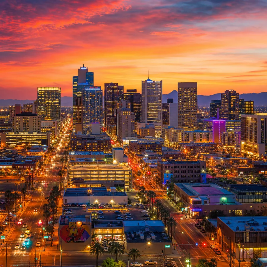 A vibrant sunset view of the Downtown Phoenix skyline with city lights illuminating the streets