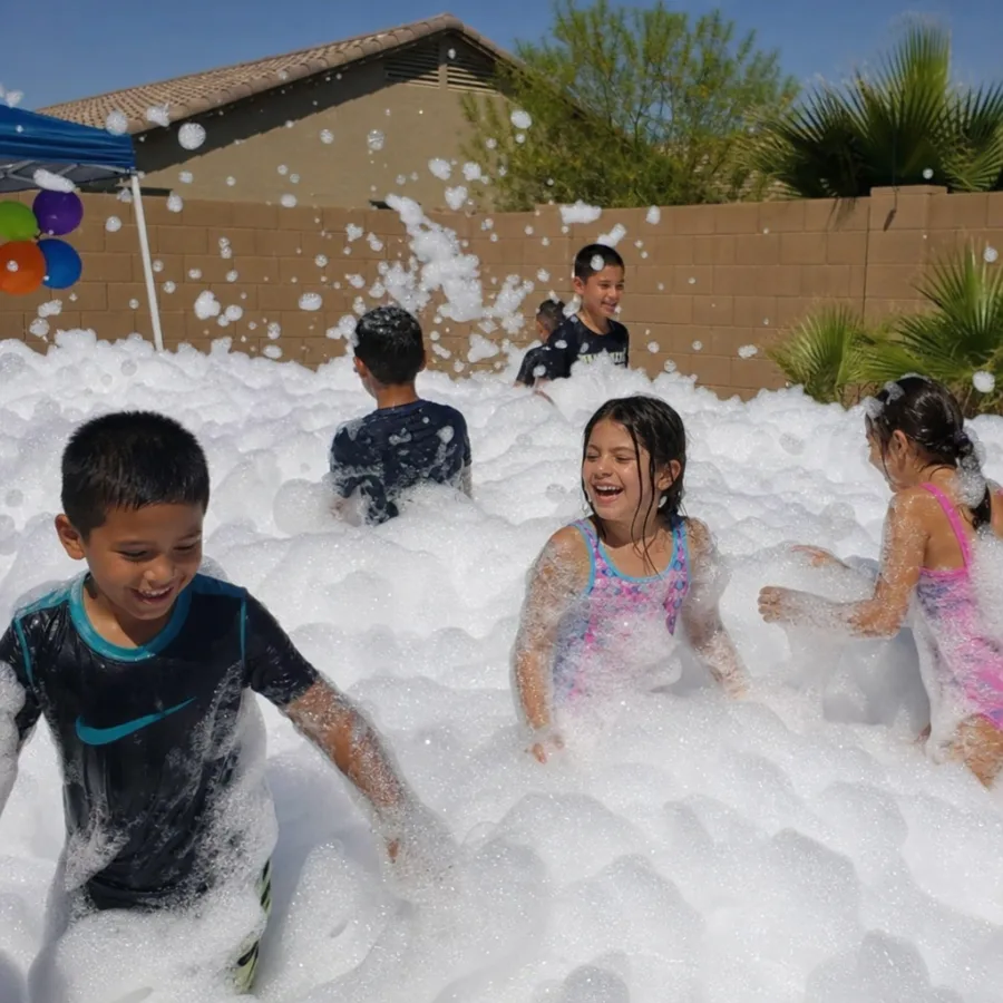 Children playing in thick white party foam in a Phoenix backyard