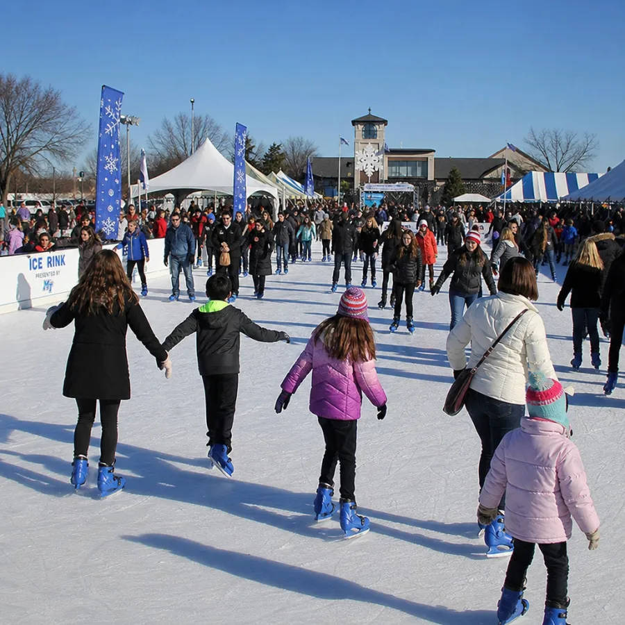 Crowd of people enjoying a large scale synthetic ice rink rental at a sunny outdoor winter festival