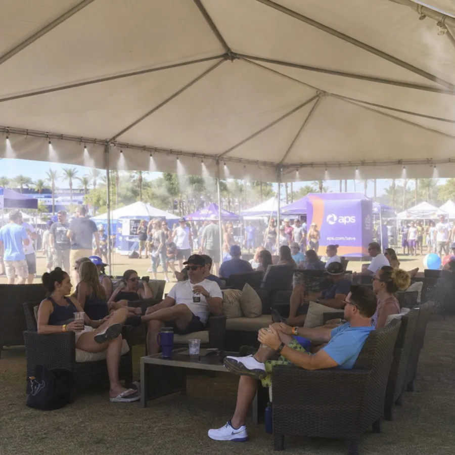 Guests relaxing under a shaded misting tent at an outdoor Phoenix event