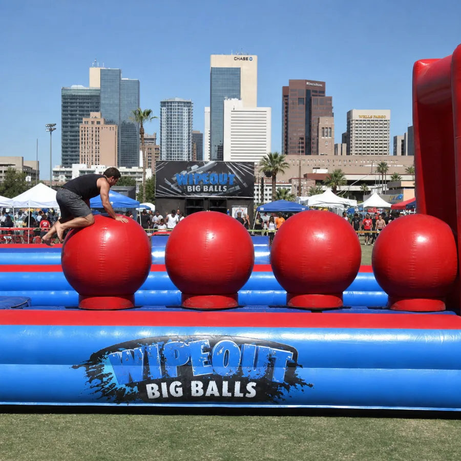 AI concept image of a Wipeout Big Balls inflatable at an outdoor event with the downtown Phoenix skyline in the background