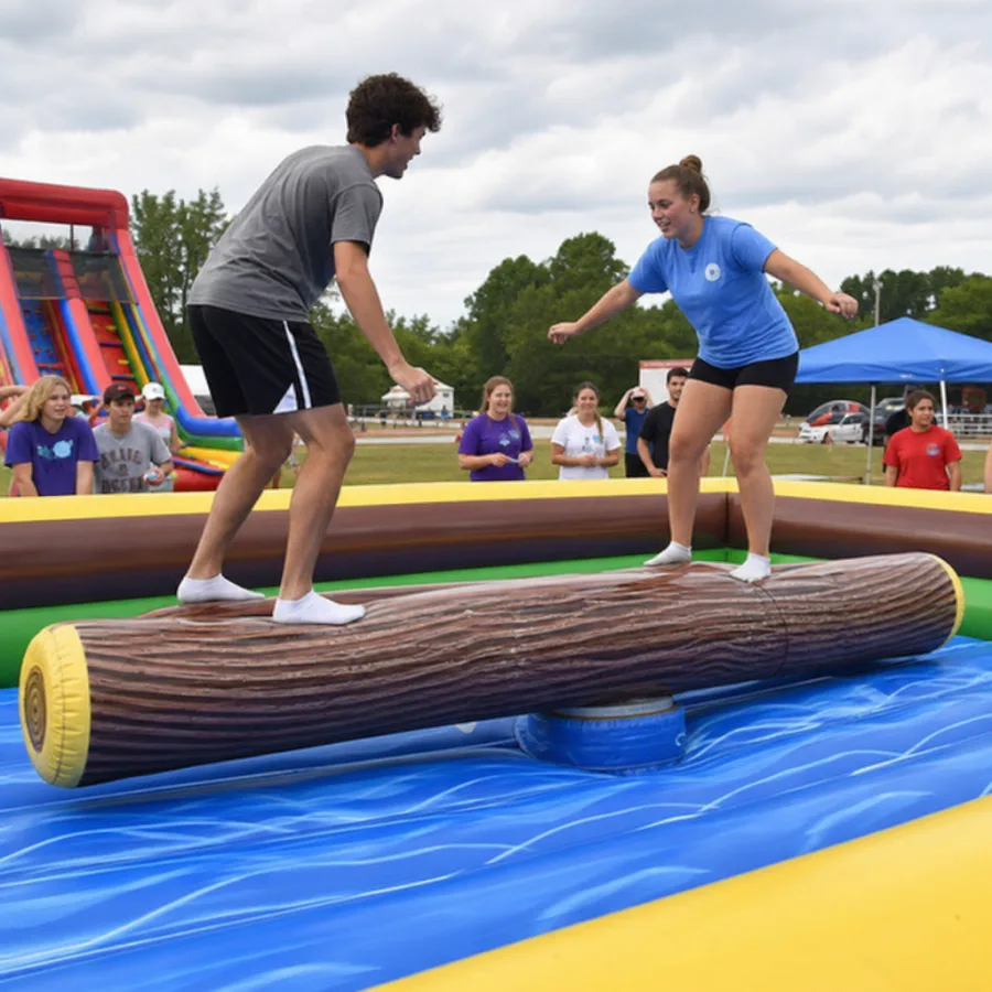 Guests competing on an inflatable log rolling rental game