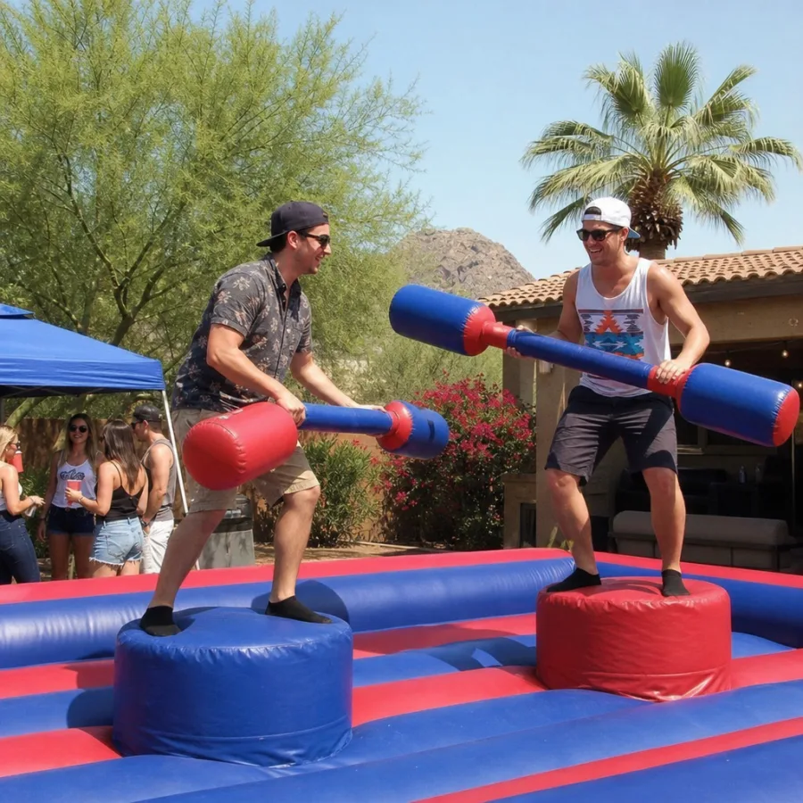 Two guests playing an inflatable joust game at an outdoor Phoenix party
