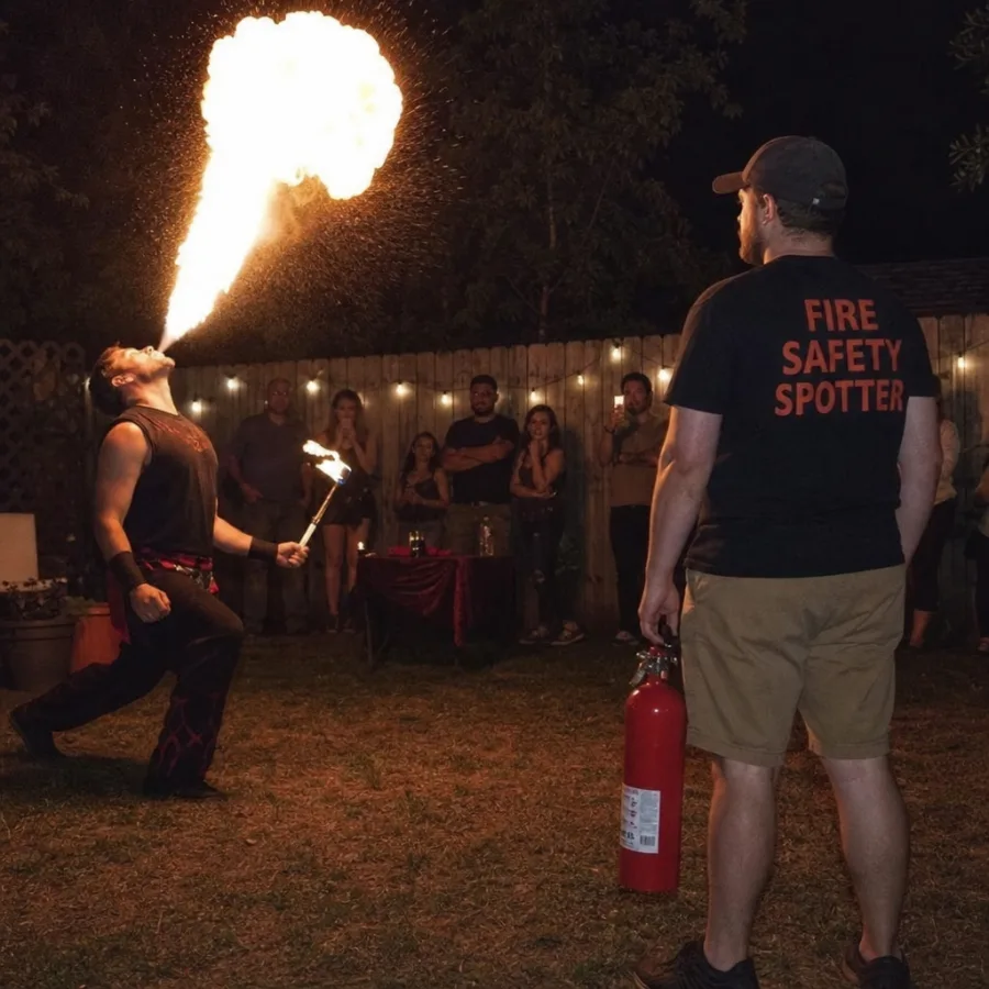 Fire safety spotter standing by with an extinguisher during a backyard fire breathing performance