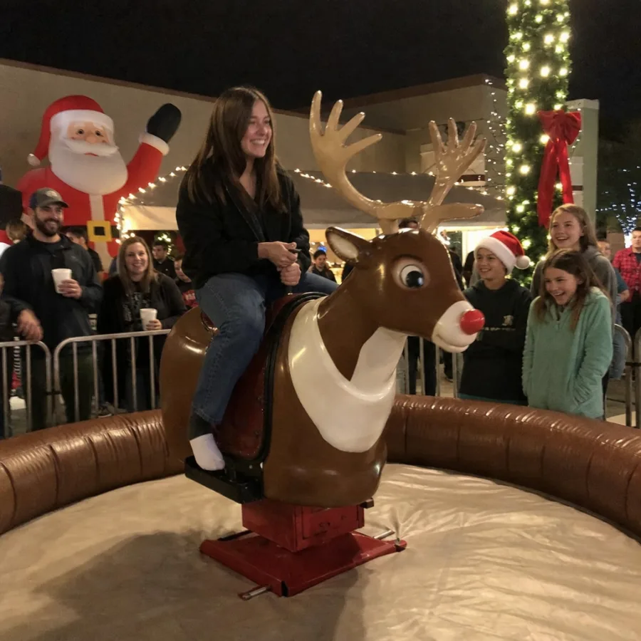 Guests enjoying a mechanical reindeer rental at a holiday event