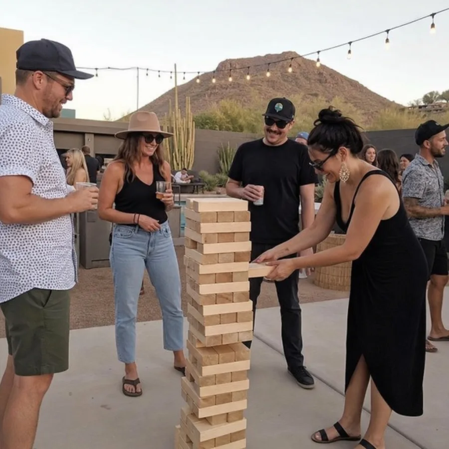 Guests playing oversized wooden block stacking game at an outdoor Phoenix party